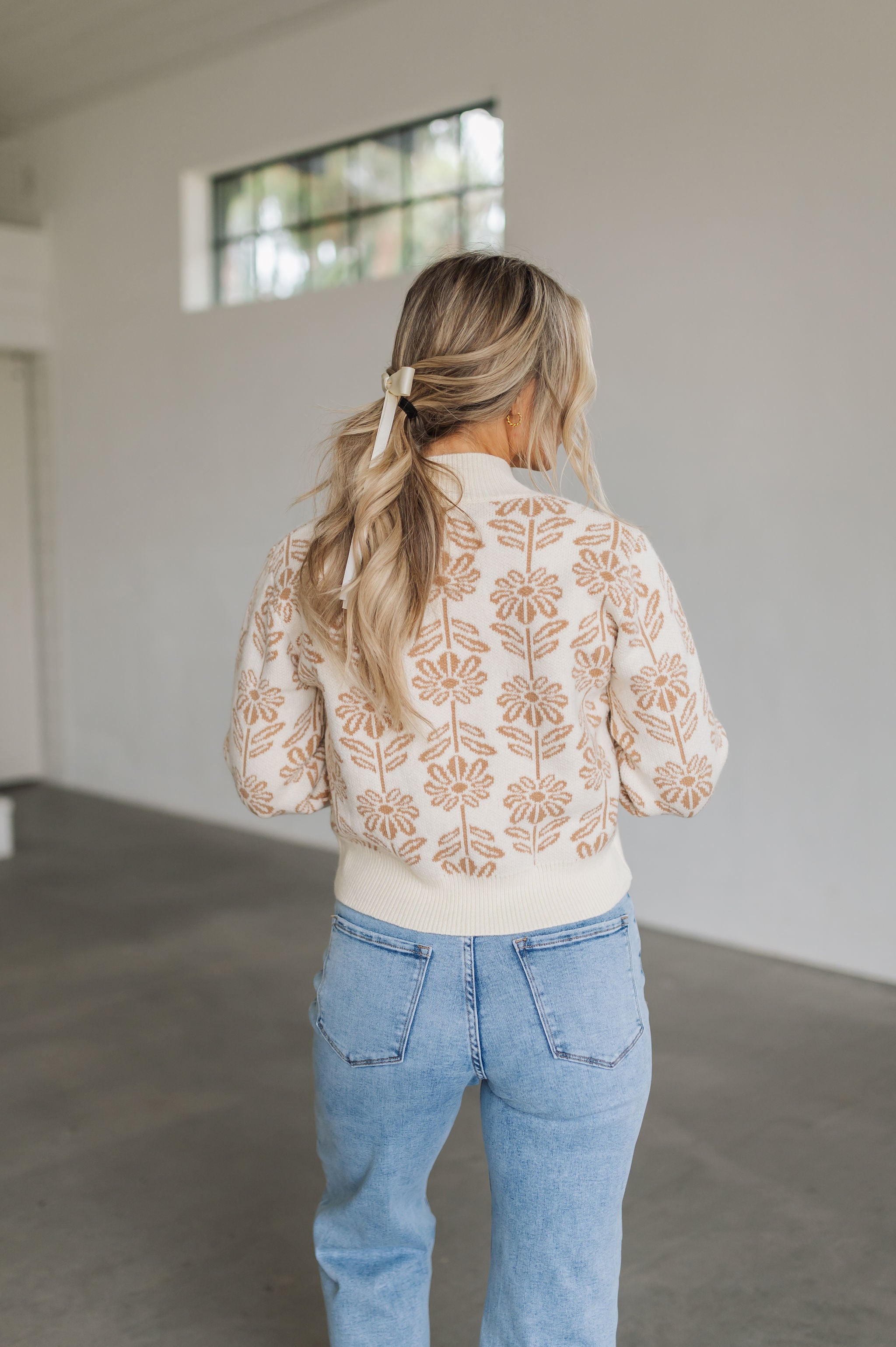 Rear view of Magnolia Knit Sweater with ribbed mock neck and hem, and allover floral pattern. 