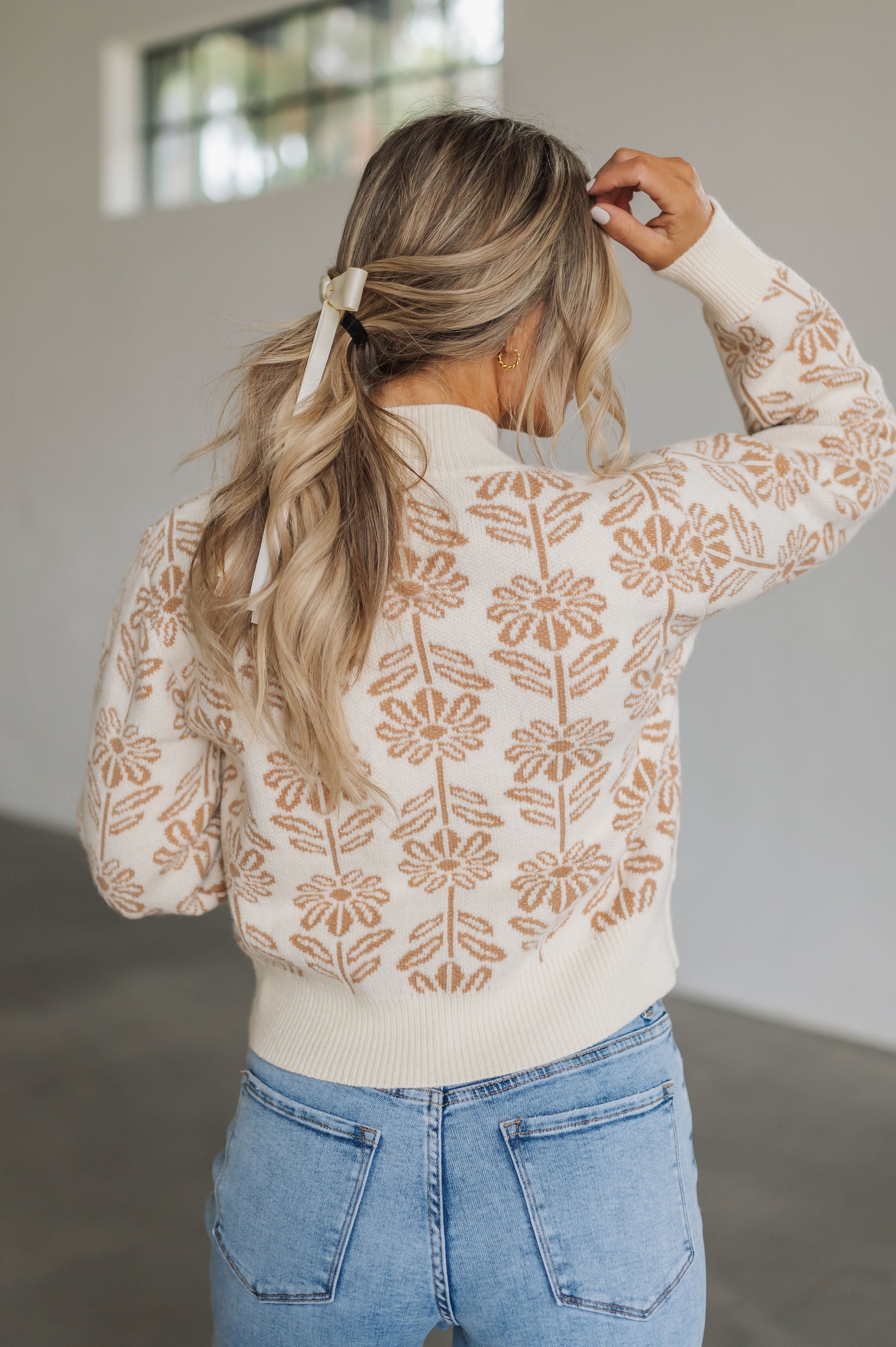 Rear view of Magnolia Knit Sweater with ribbed mock neck, hem, and cuffs, and allover floral pattern. 