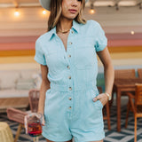 Front view of button up Cannon Romper with elastic waistband, side seam pockets,  and cuffed sleeves and hem.