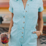 Close up front view of button up Cannon Romper with elastic waistband, cuffed sleeves and hem, and chest pockets.