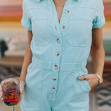 Close up front view of button up Cannon Romper with elastic waistband, cuffed sleeves and hem, and chest pockets.