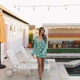 Front view of floral patchwork crochet Vacay Mini Coverup with long sleeves, scalloped edges, deep V neckline, and tie front.