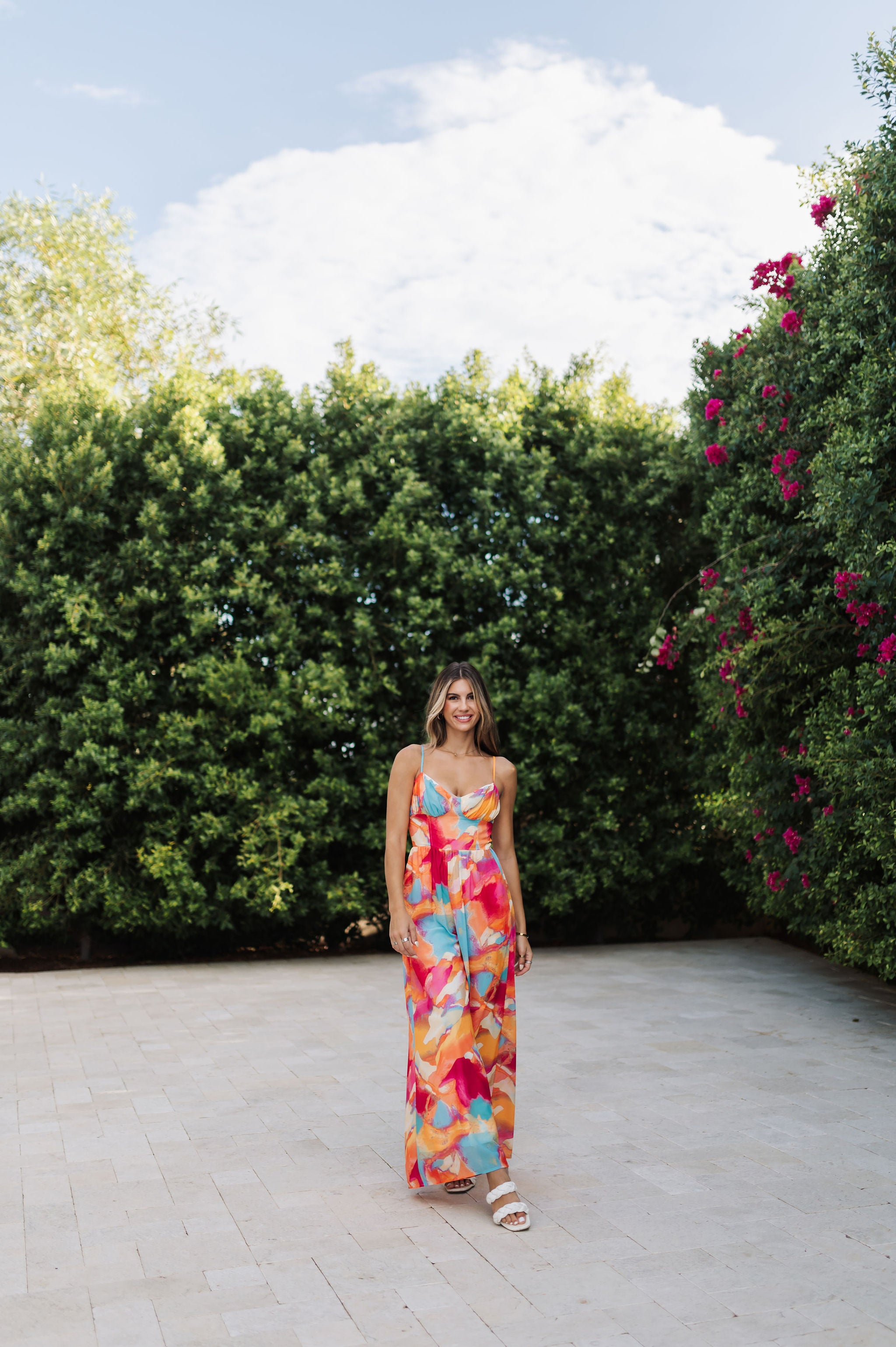 Front view of Golden Hour Jumpsuit in bright water color print, thin straps, bustier top, and wide legs. 