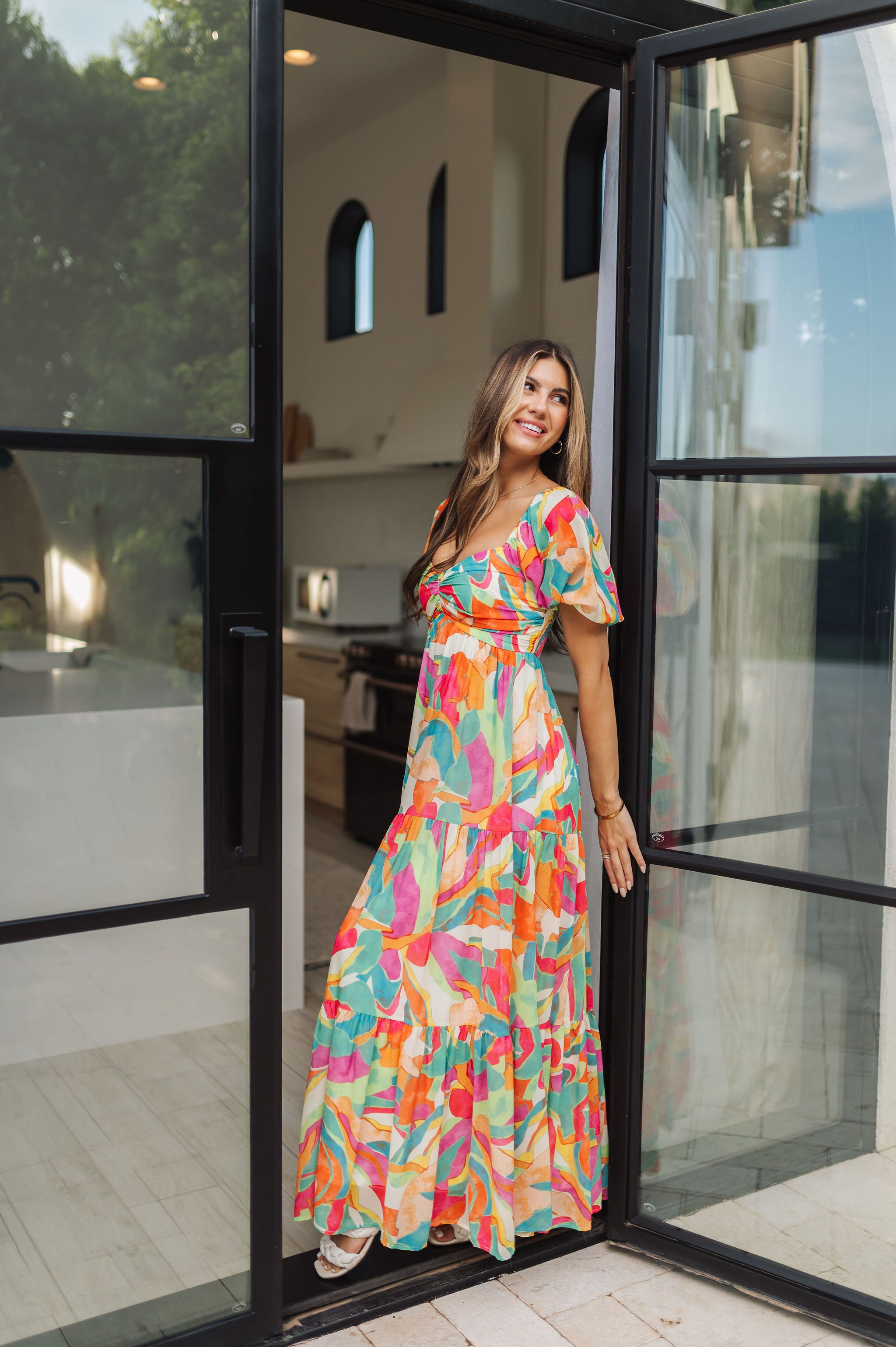 Side view of  Isle Glow Maxi Dress in allover bright floral print with short puff sleeves, sweetheart neckline, and ruffle hem. 