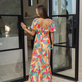 Rear view of  Isle Glow Maxi Dress in allover bright floral print with short puff  sleeves, smocked back, and ruffle hem. 