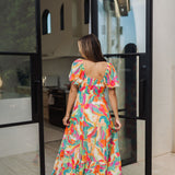 Rear view of  Isle Glow Maxi Dress in allover bright floral print with short puff  sleeves, smocked back, and ruffle hem. 