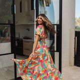 Side rear view of  Isle Glow Maxi Dress in allover bright floral print with short puff sleeves and a ruffle hem. 